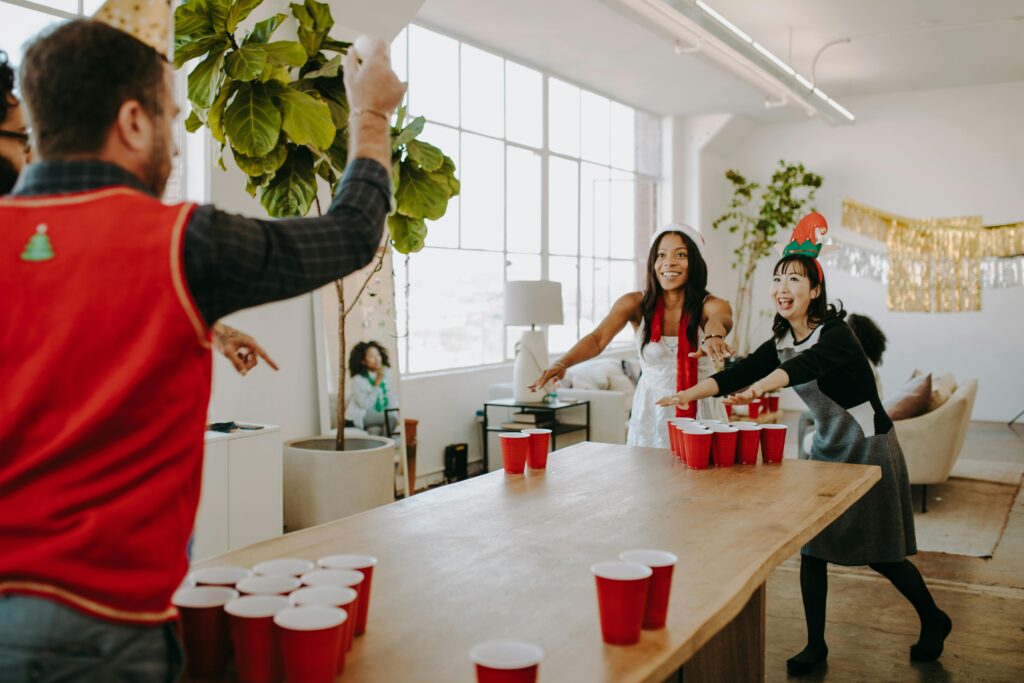 Autour d'une longue table, des adultes sont en train de jouer au moment de Noël. 