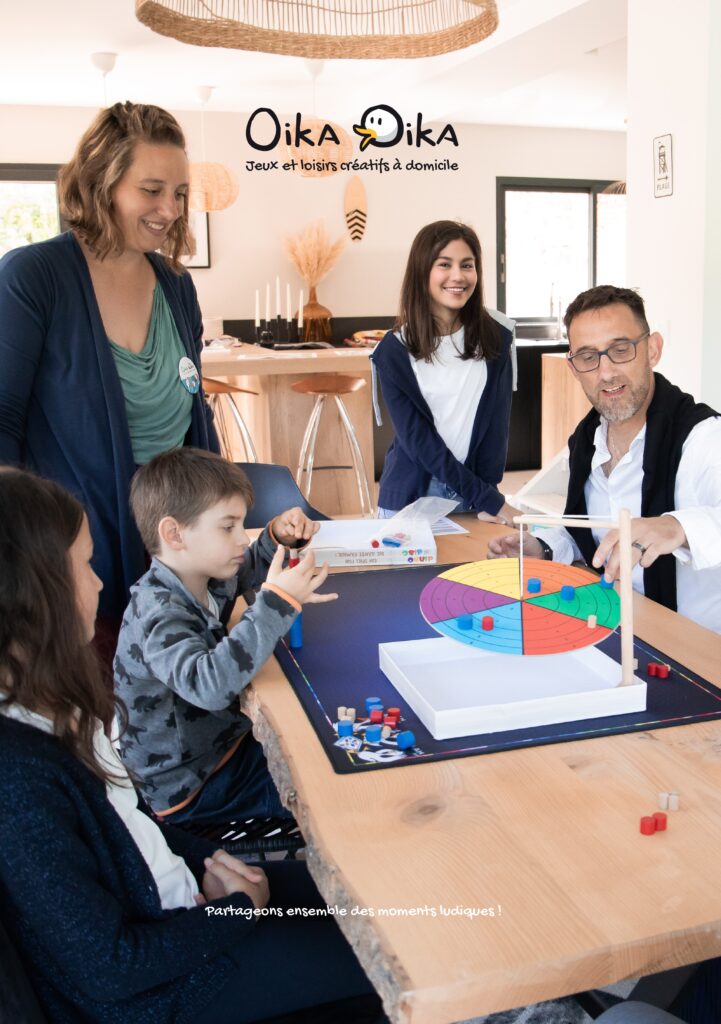 un homme, une femme, 3 enfants jouent à un jeu d'équilibre sur une table dans une maison